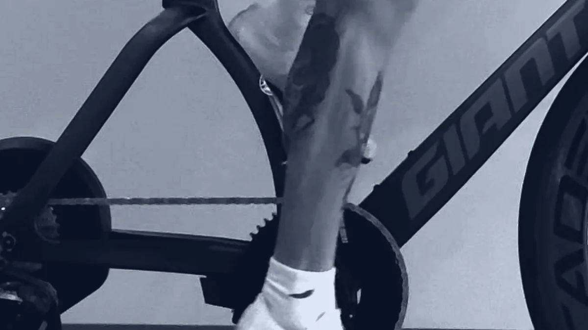 Close-up of a time-trial bike's crank and chainring with the rider's leg mid-stroke